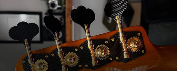 Hands adjusting guitar tuning hardware on a workshop table